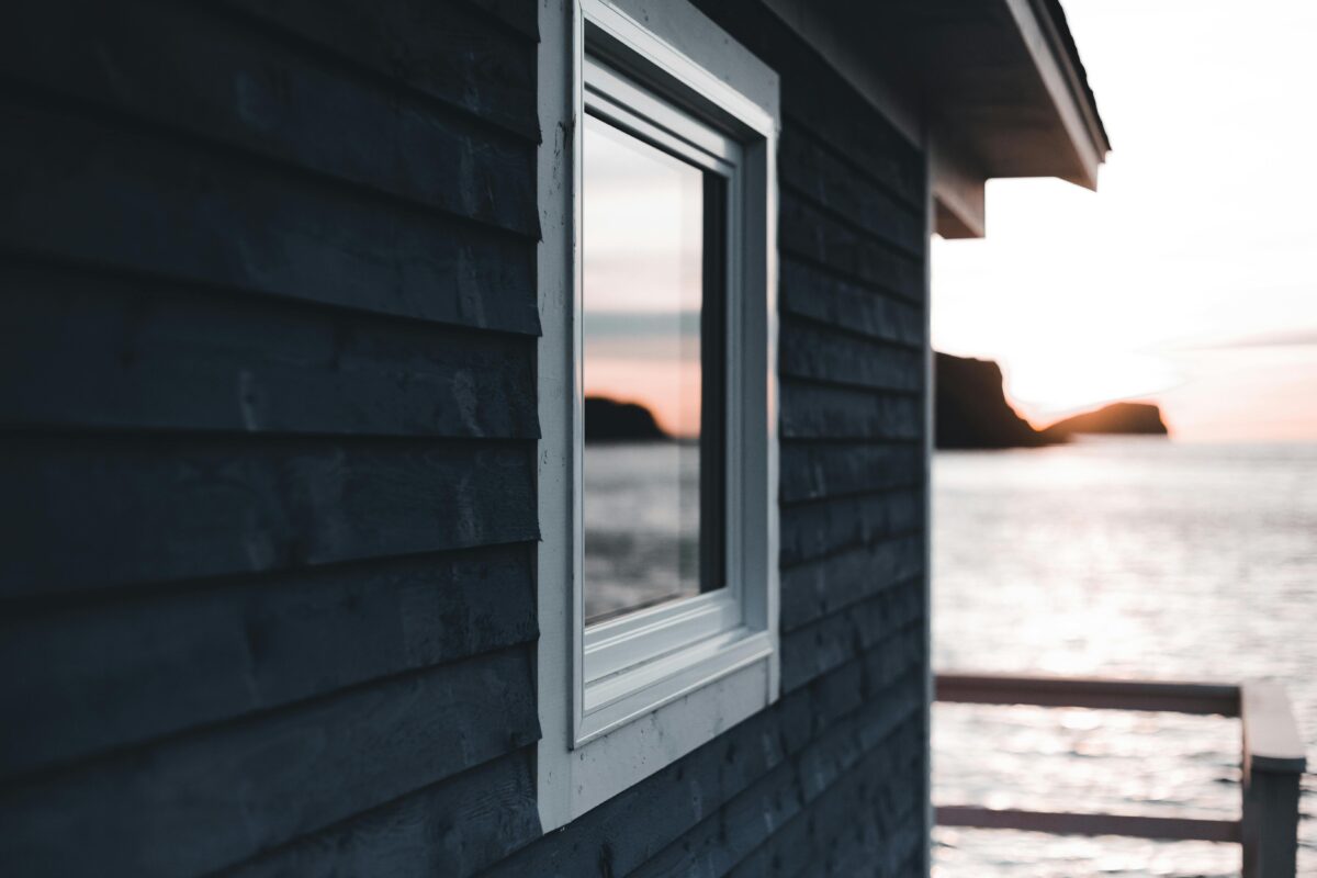 Stylish white window set in a green wooden house exterior. Perfect for architecture themes.