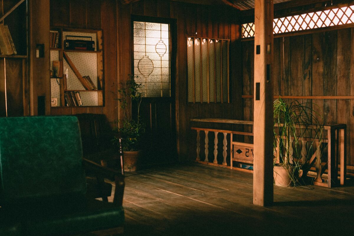A warm, rustic indoor living room with wooden decor, plants, and bookshelves.
